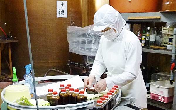 特注のごましょうゆラベル貼り作業機械より早くベテランさんが貼ります